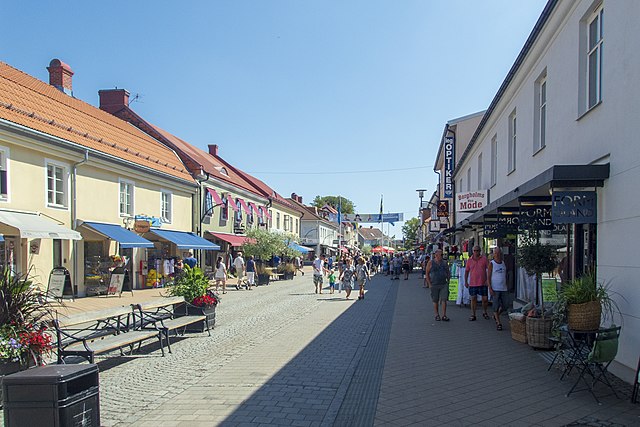 Blå himmel och över Storgatan i Borgholm. Folk rör sig mellan butikerna.
