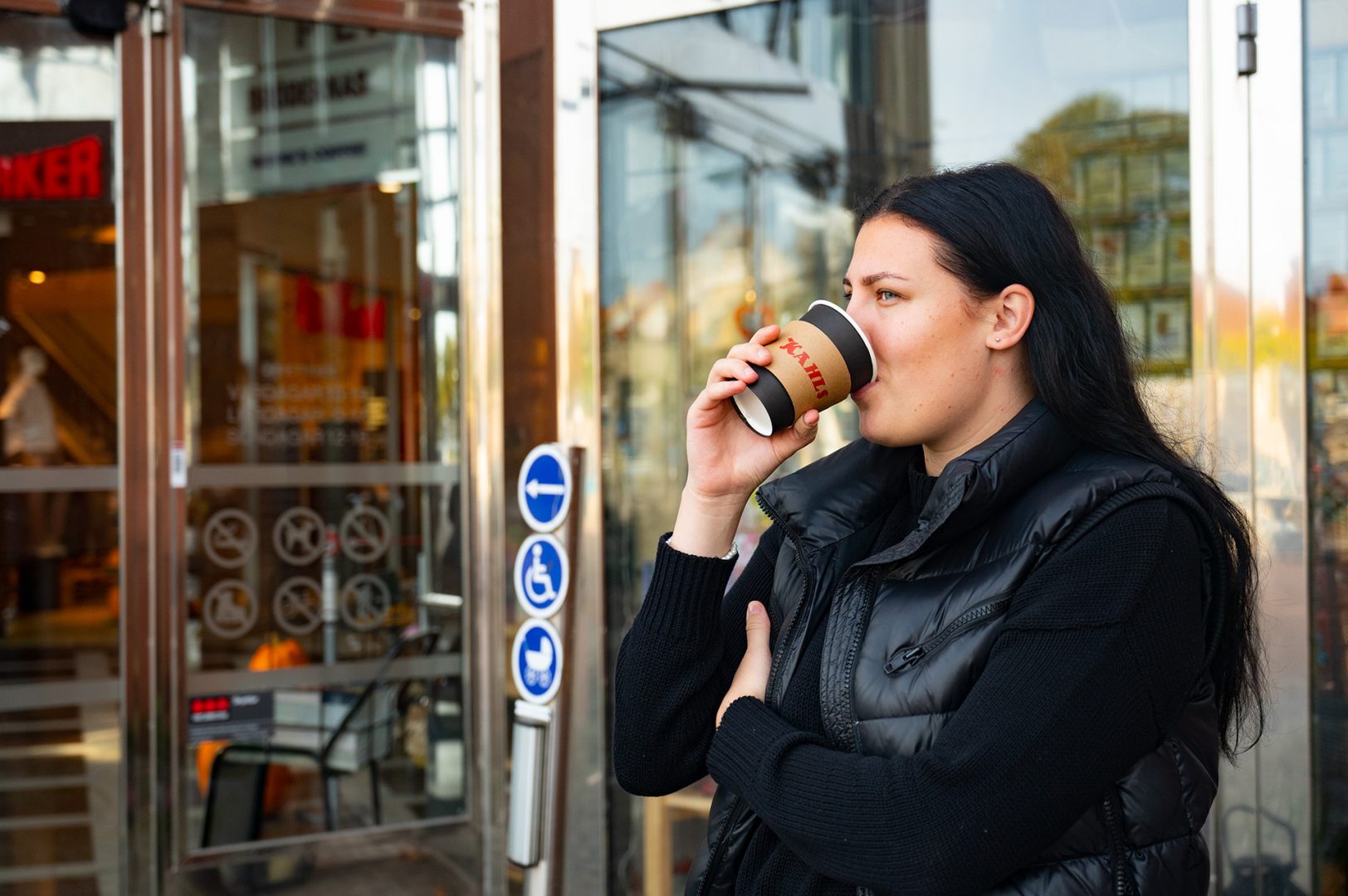 Lovisa Johansson står och dricker kaffet från Kahls och tittar bort.