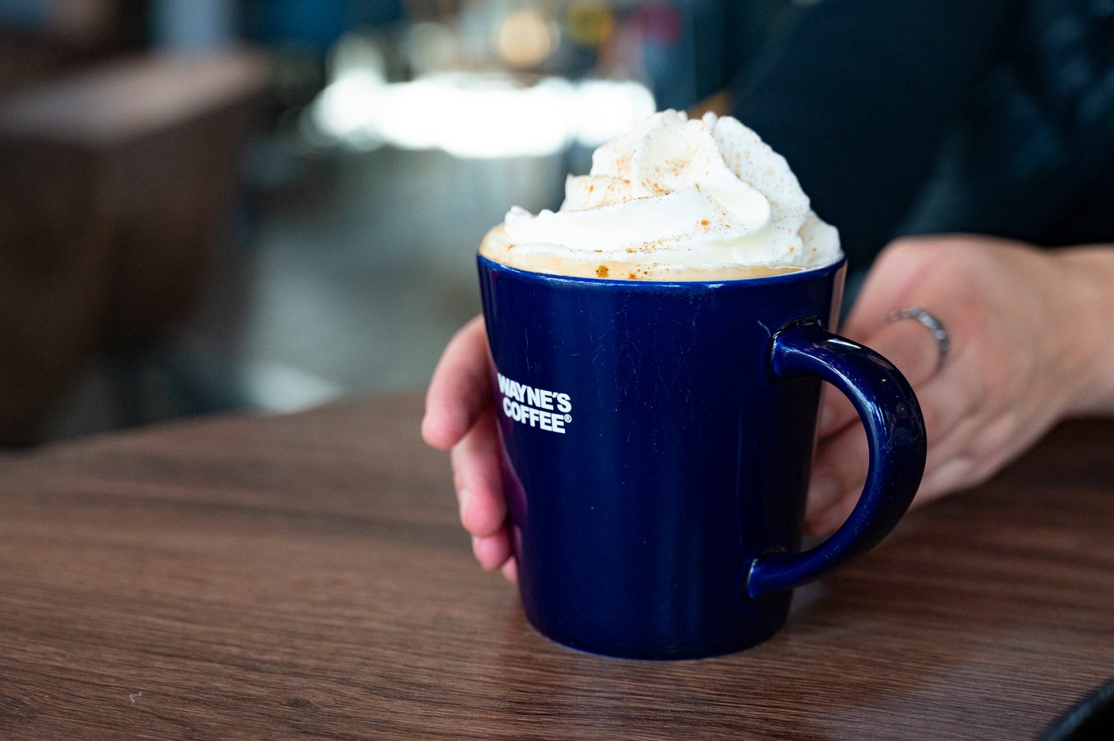 En bild på en kopp av kaffe från Waynes coffee med grädde på toppen. 