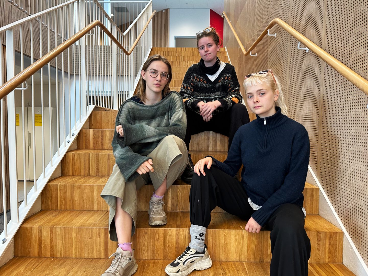 De tre medlemmarna av SMMC, Viktorija Baltušyte, Jojenneke Van Duijn och Lena Sammiller sitter i en trappa och tittar mot kameran med en seriös blick.