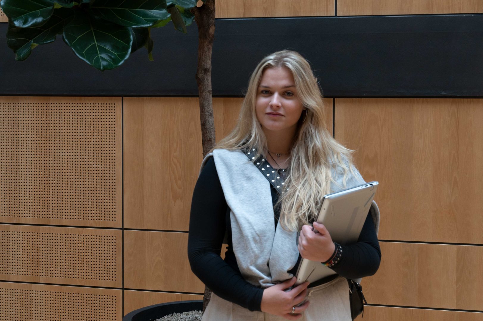 Nikolina Lekic står med en dator i handen, inne på Linnéuniversitetet i Kalmar.