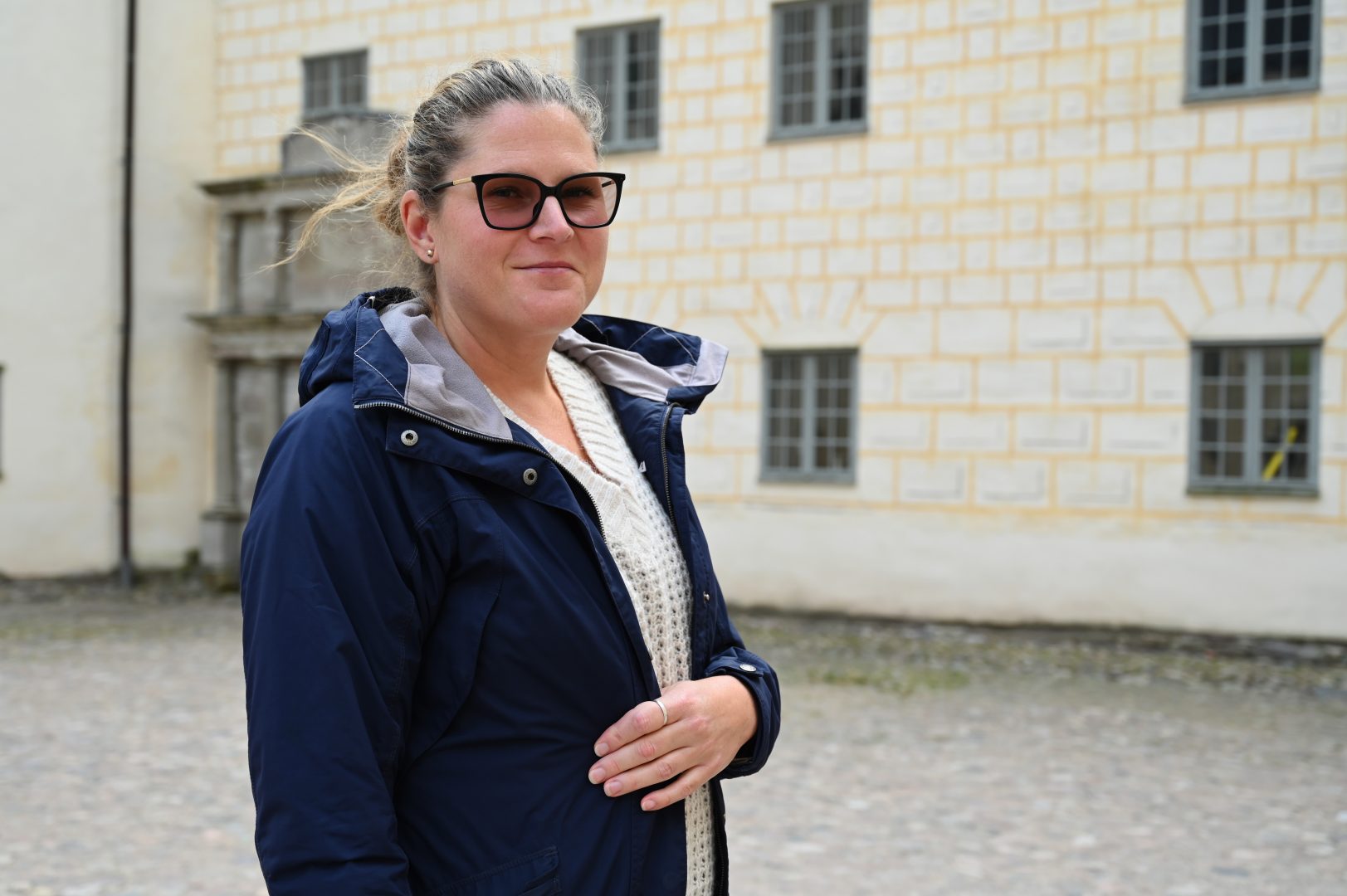 Johanna Algotsson på slottets innergård. Kollar in i kameran, står snett till vänster.