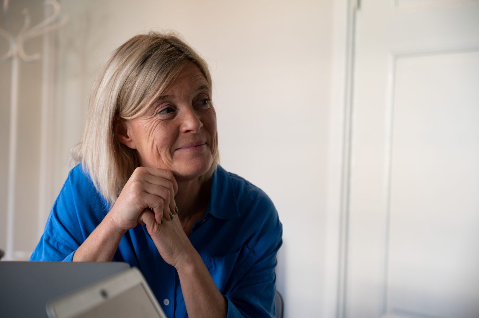 Maria Lexner tittar till höger och har ett litet leende på läpparna. Hon sitter till vänster om bilden framför en vit vägg. Hon bär en blå tröja på sig.