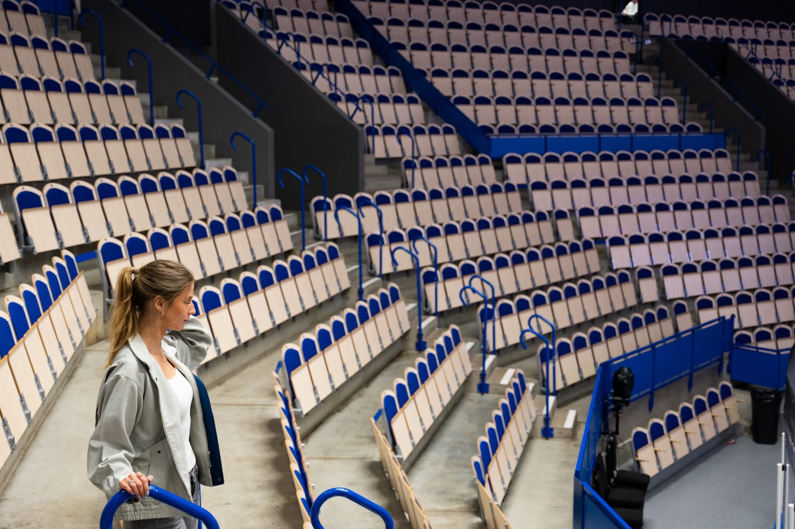 Reporten såt bland läktarna och tittar mot mitten av arenan. Hon står till vänster i bilden.