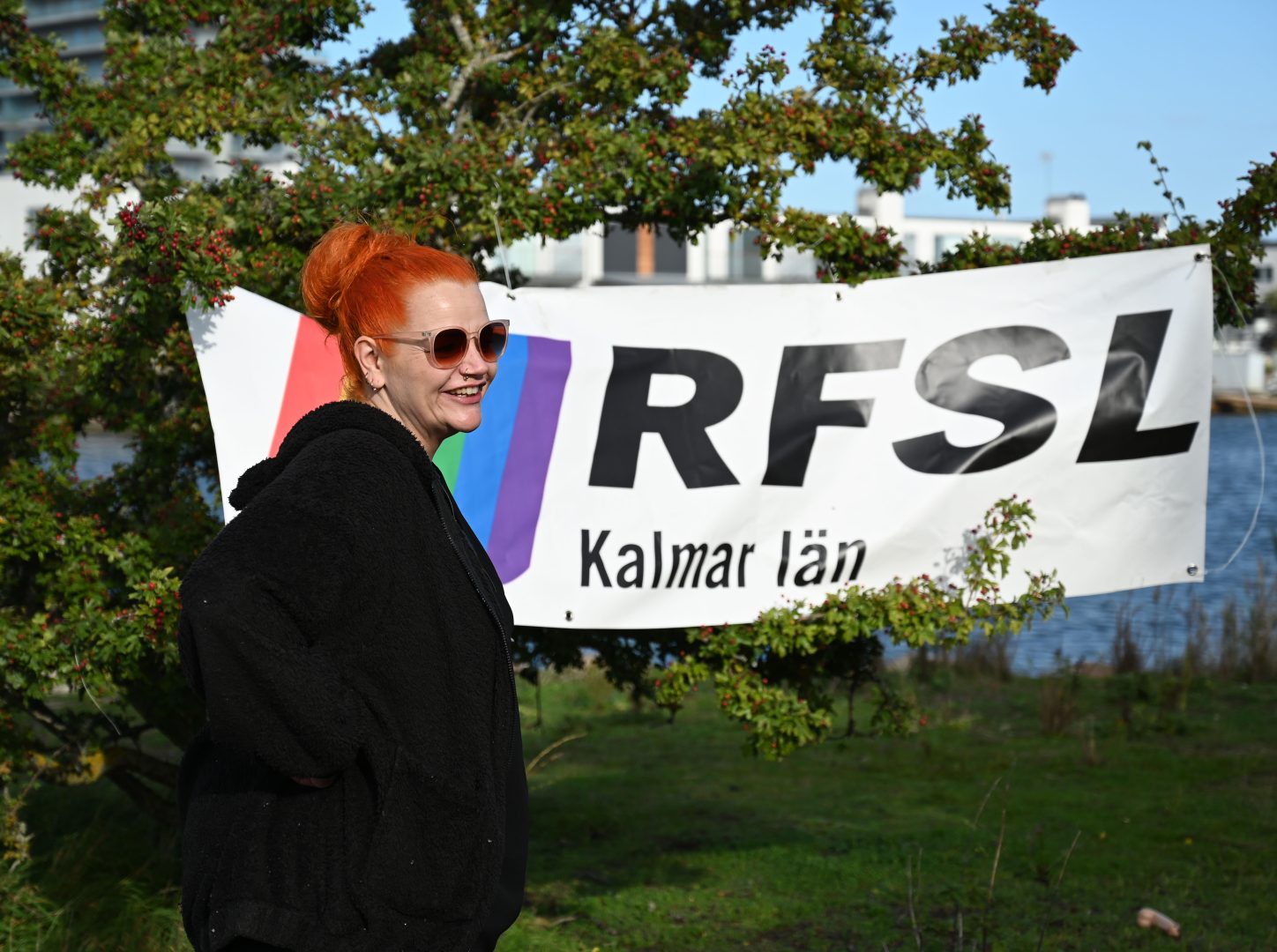Ida Curtsdotter Karjo, ordförande för RSFL står framför en skylt som sitter i ett träd med loggan RSFL.