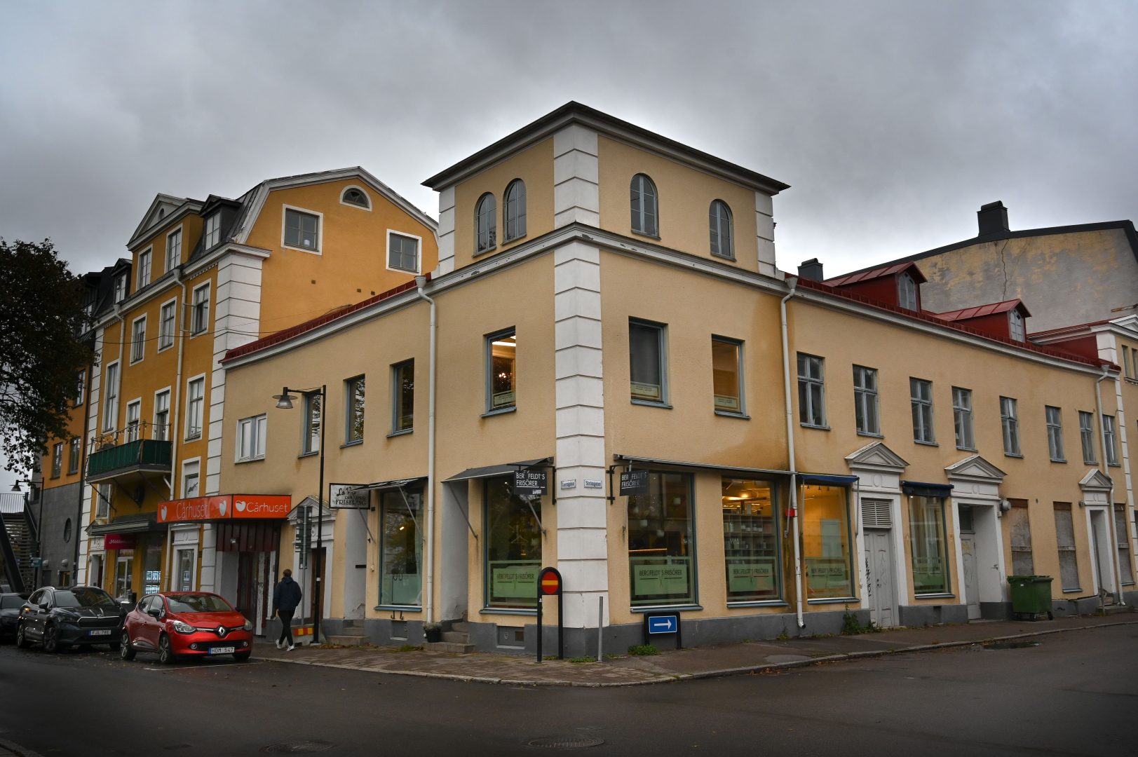 En gul byggnad och en man som går på trotoaren.