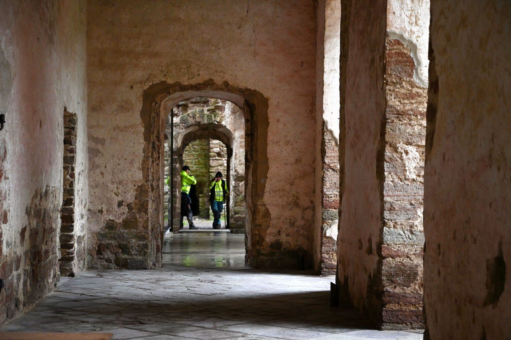 Bild i en korridor i Borgholms slottsruin, där byggarbetare står långt in och pratar.