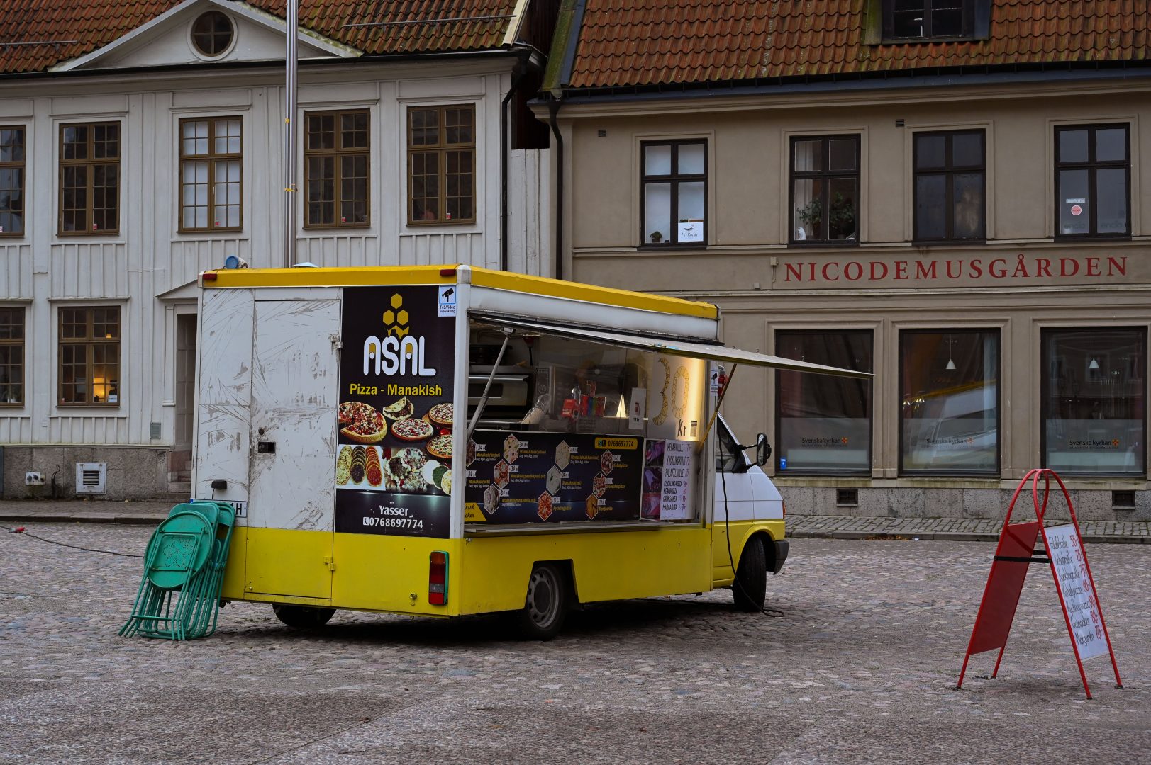 En foodtruck på ett torg med byggnader i bakgrunden.