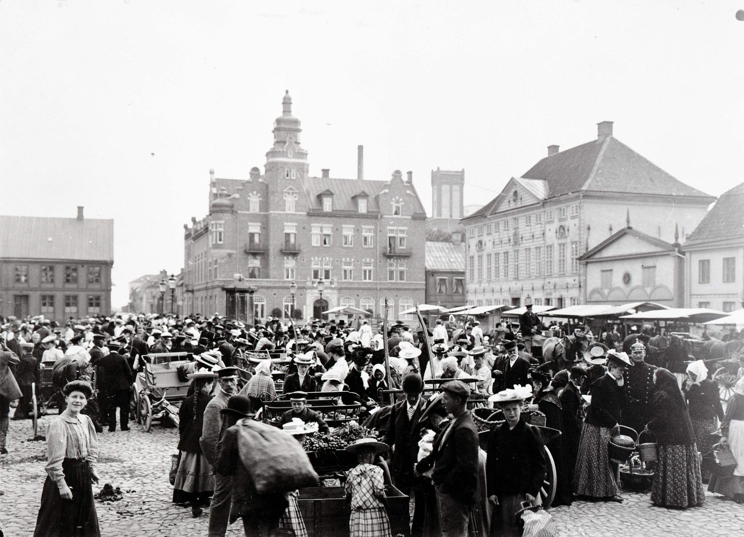 En samling männsiskor på ett torg med byggnader i bakgrunden.