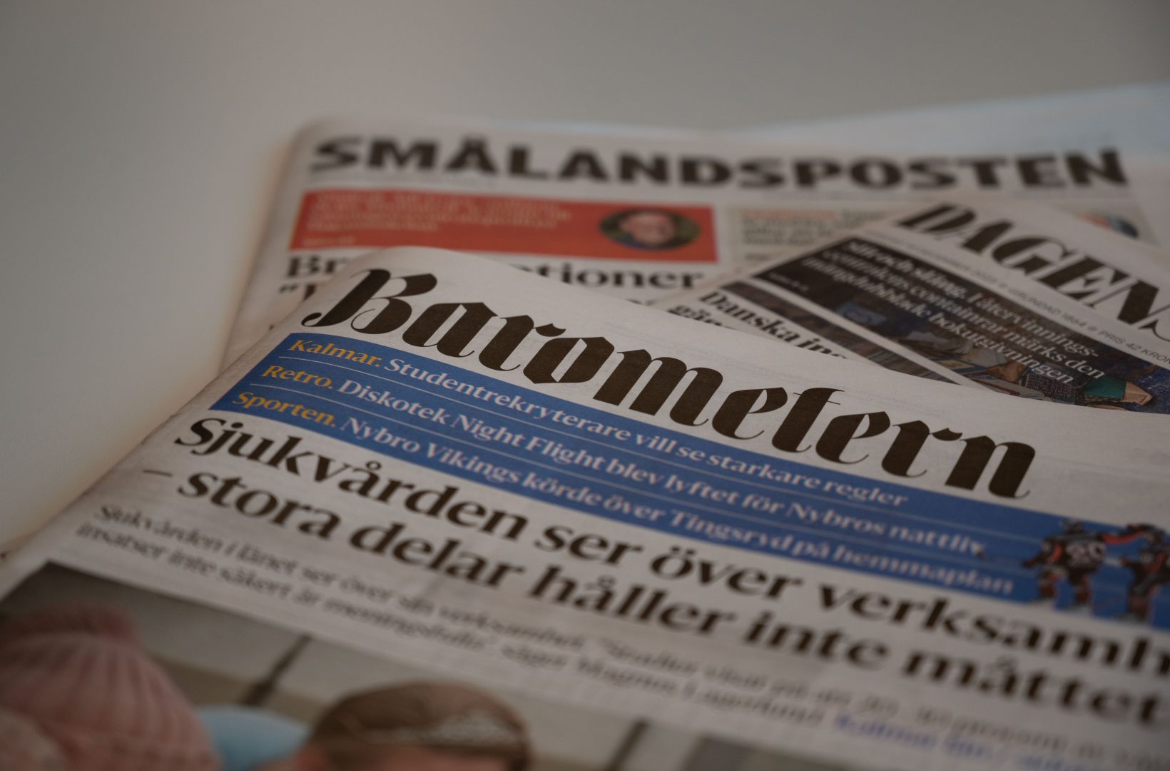 En hög med dagstidningar ligger på ett bord. Barometern-tidningen ligger högst upp i högen.