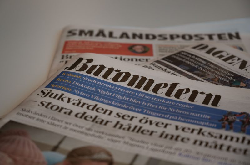 En hög med dagstidningar ligger på ett bord. Barometern-tidningen ligger högst upp i högen.