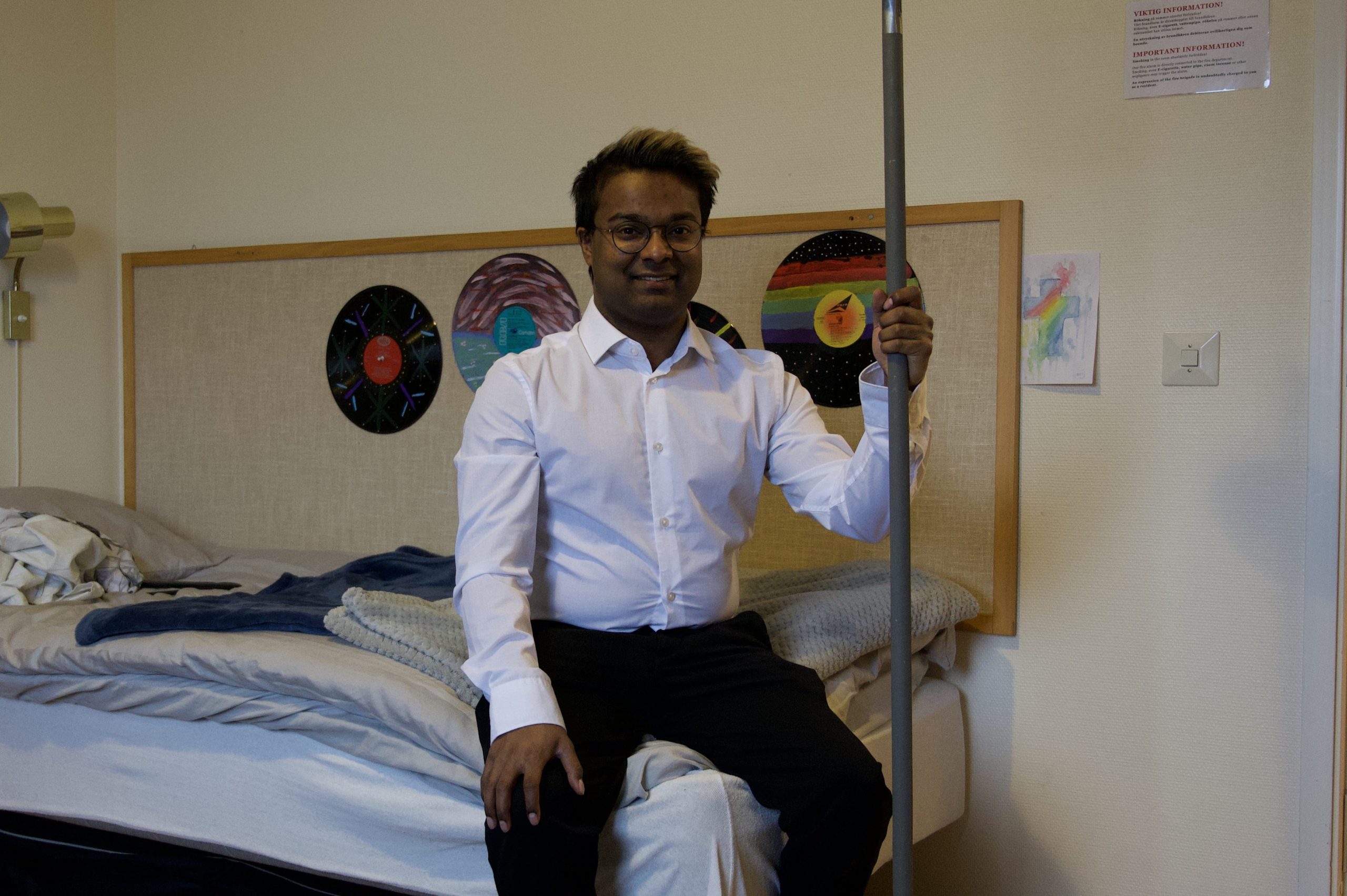 Adam sitter på sin säng i rummet på folkhögskolan. 