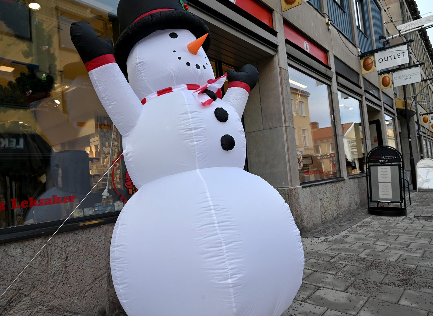 En vit uppblåsbar snögubbe står utanför en leksaksbutik.