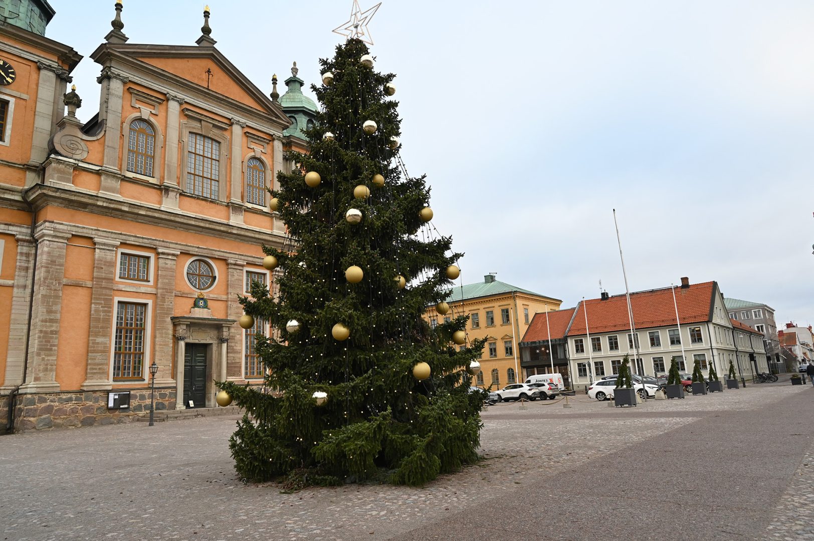 En stor julgran på Stortorget i Kalmar. Det hänger ljusslingor och guldiga och glittriga julkulor i den.