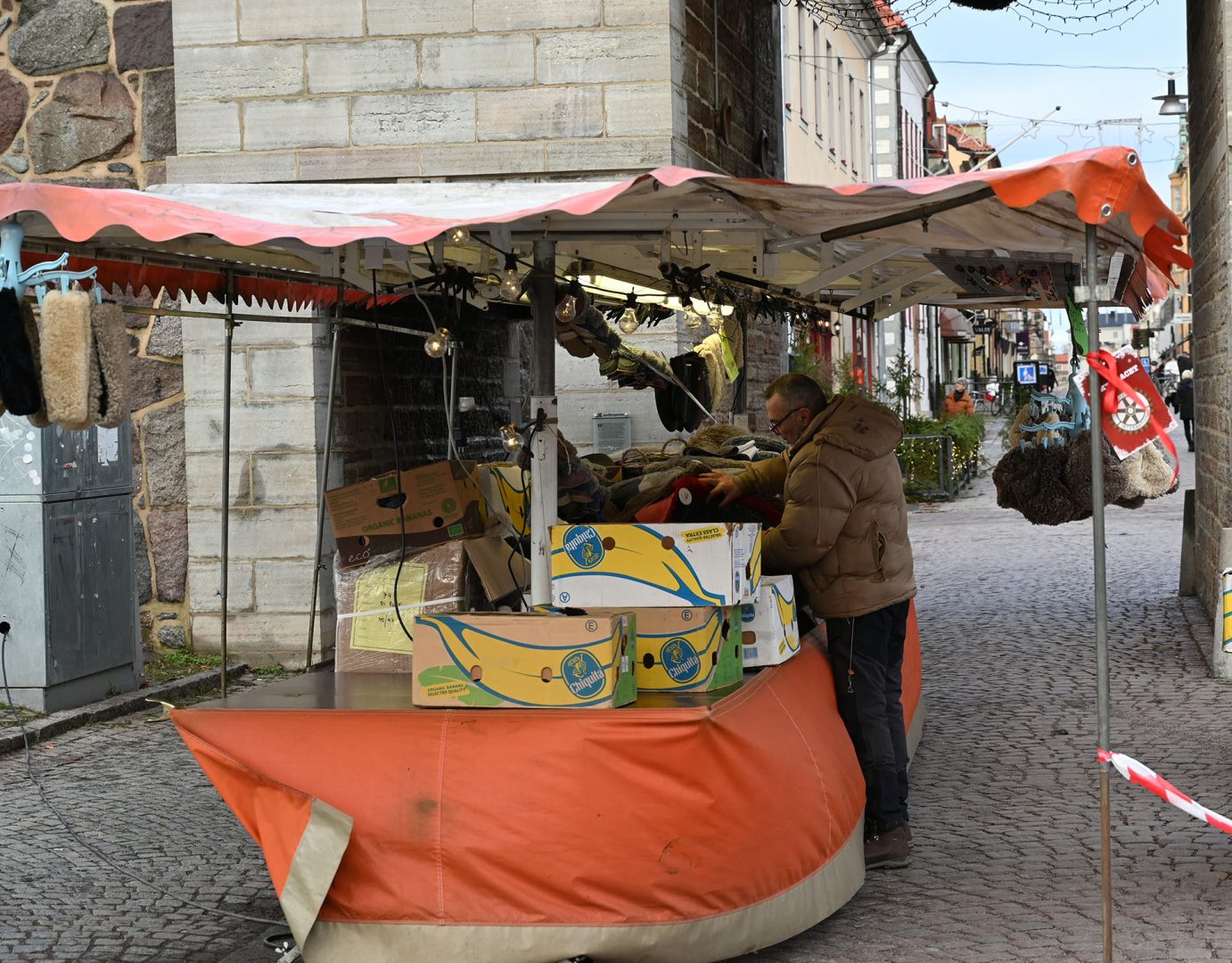En man som står och säljer textilier i fårskinn vid muren i Kalmar.