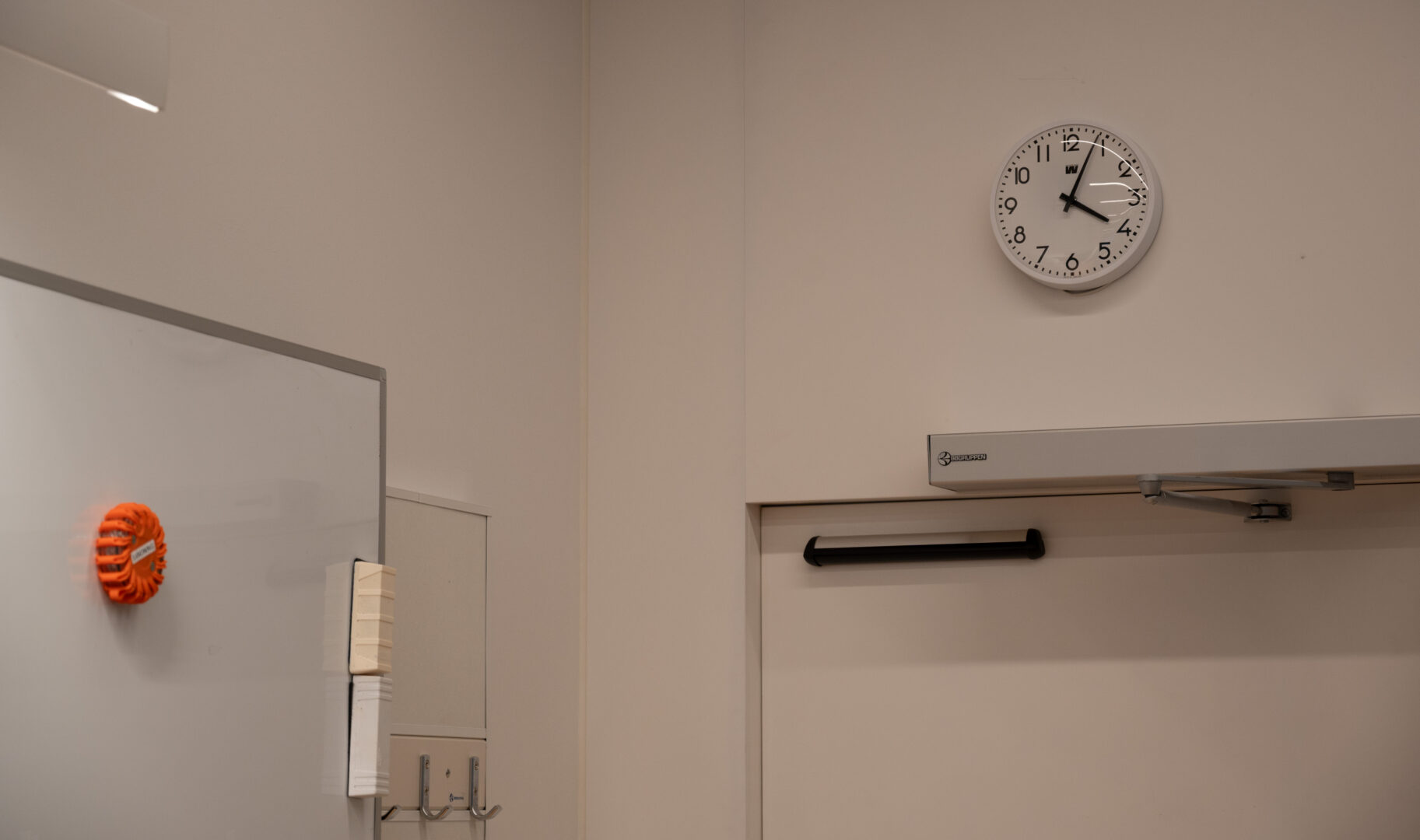 Bilden föreställer en analog klocka ovanför en dörr i ett klassrum.