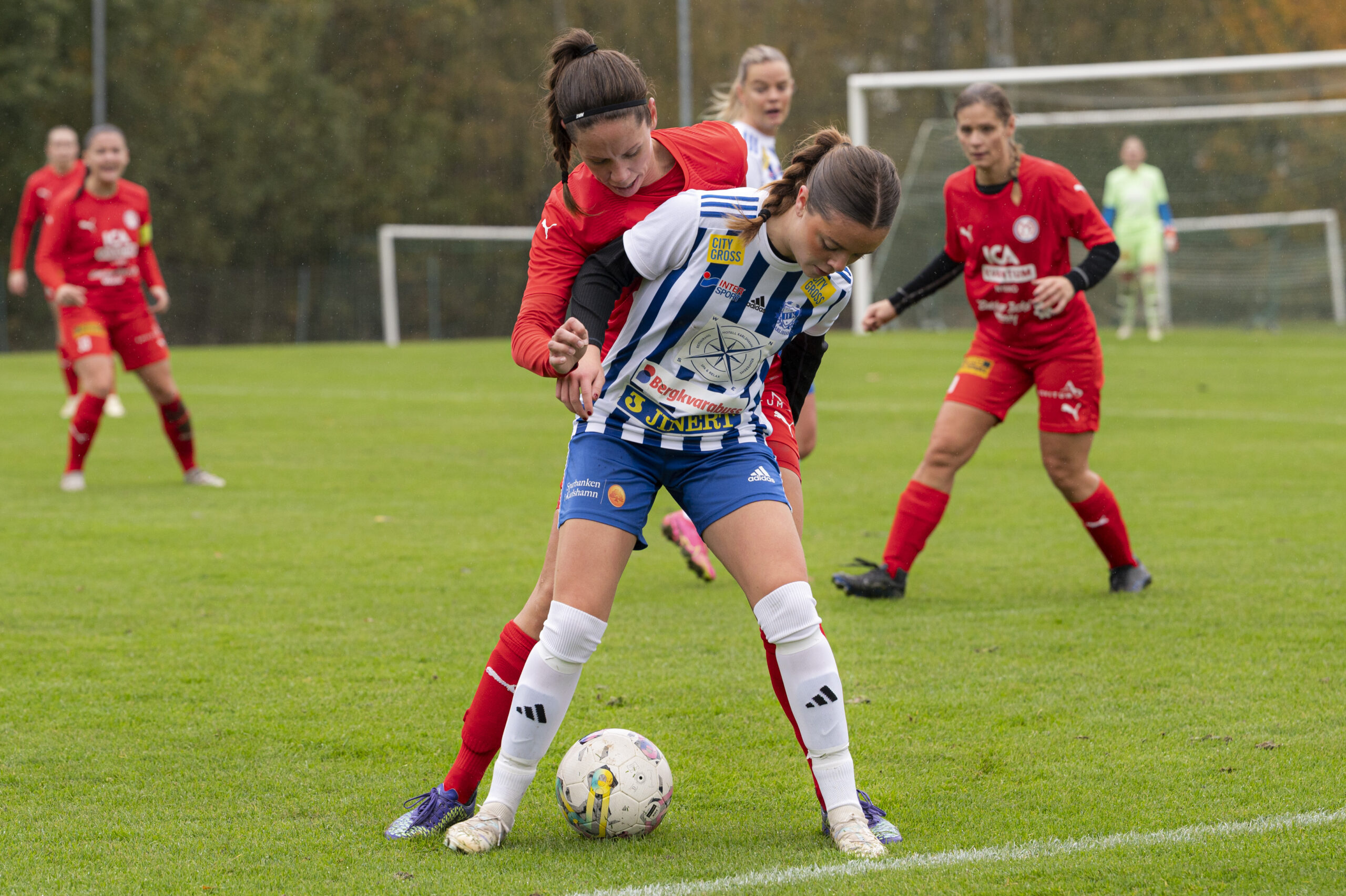 Hannah Ekström från Madesjö IF i rött i en närkamp om bollen mot IFK Karlshamns Violetta Burgos i vitt på Madesjövallen i Nybro. Foto: Kajsa Sjöberg.