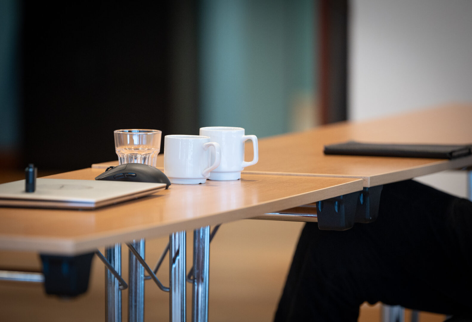 Två kaffekoppar trängs med datorer på ett bord.