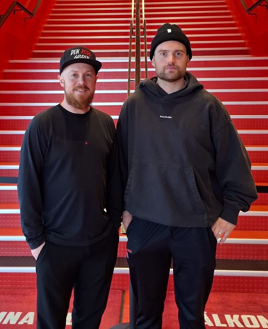 Två män i svarta kläder framför en röd trappa