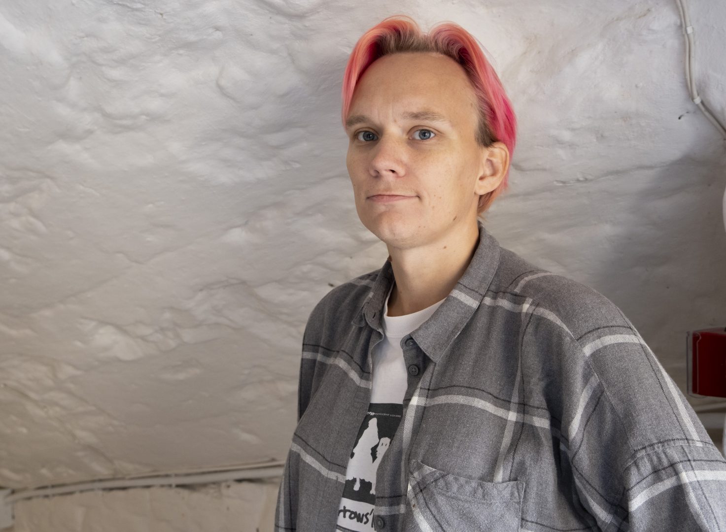 Andrea Reventon, ordförande i RFSL Kalmar län, tittar in i kameran framför en sten vägg.