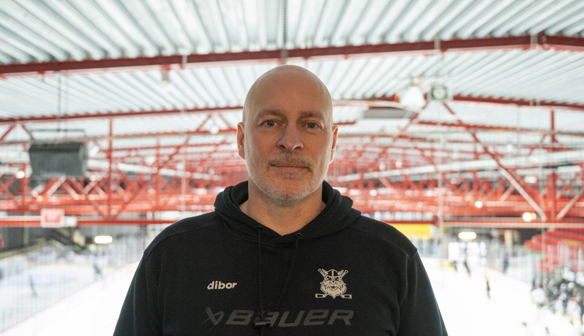 En man står i Liljas Arena iklädd svart hoodie med Nybro Vikings logotyp.