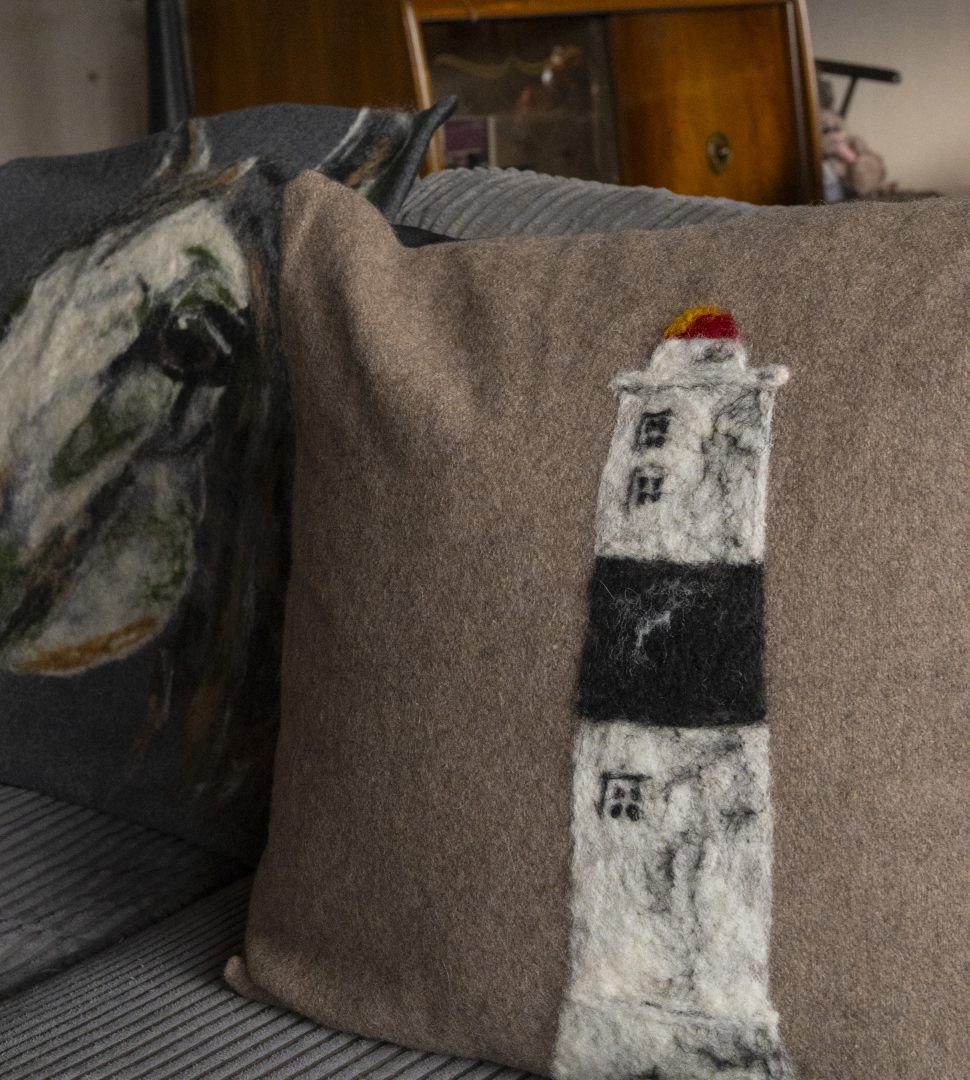 Två ullkuddar, en i motivet av en fyr, den andra i motivet av en häst.