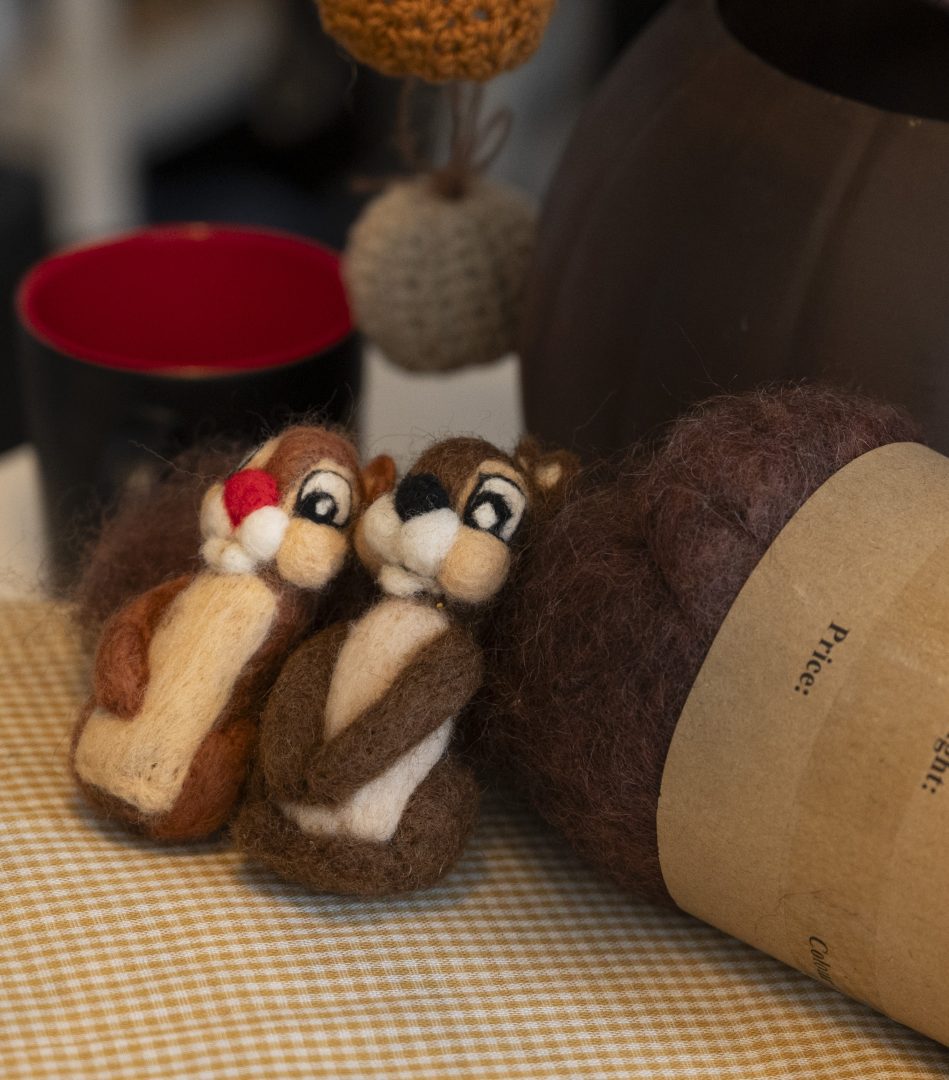 Två ekorrar i ull står lutade mot brunt garn.