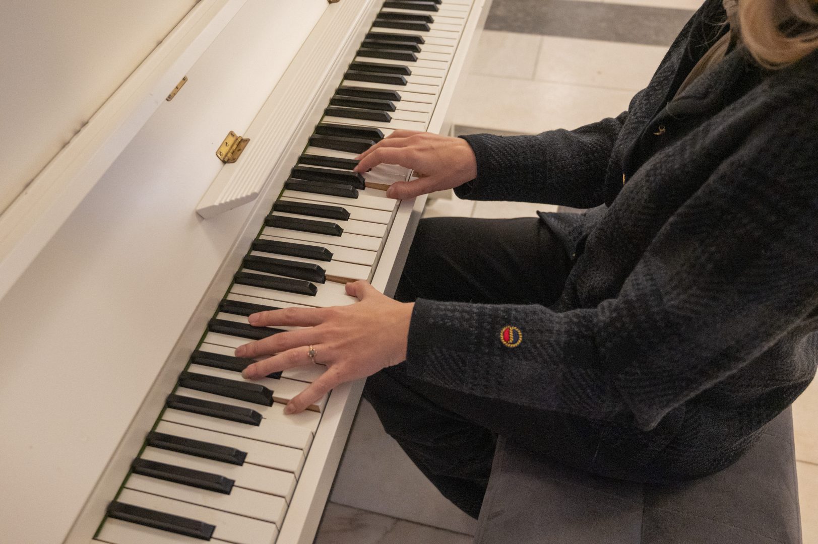 En person spelar på ett vitt piano, fångad mitt i en melodi.