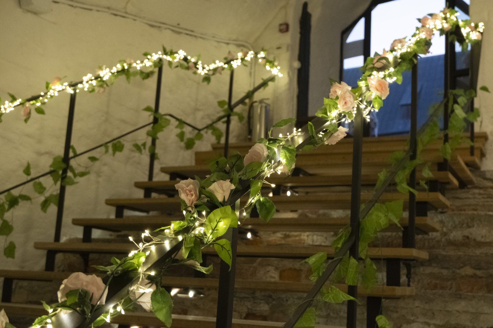 En trappa men blommor och ljusslingor på räcket. 