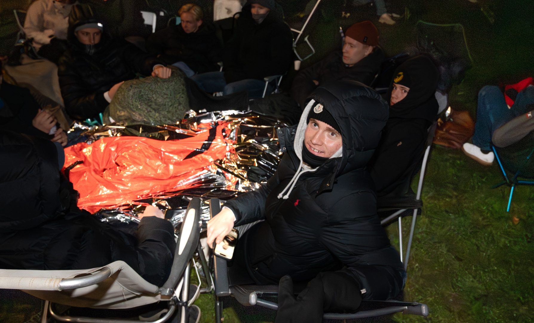 Benjamin Larsen sitter på en brassestol med sina kompisar. Det är mörkt ute och han har tjocka kläder på sig.