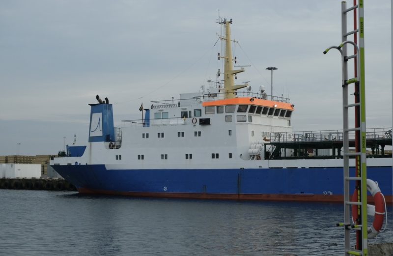 En blå och vit båt som ligger i en industihamn