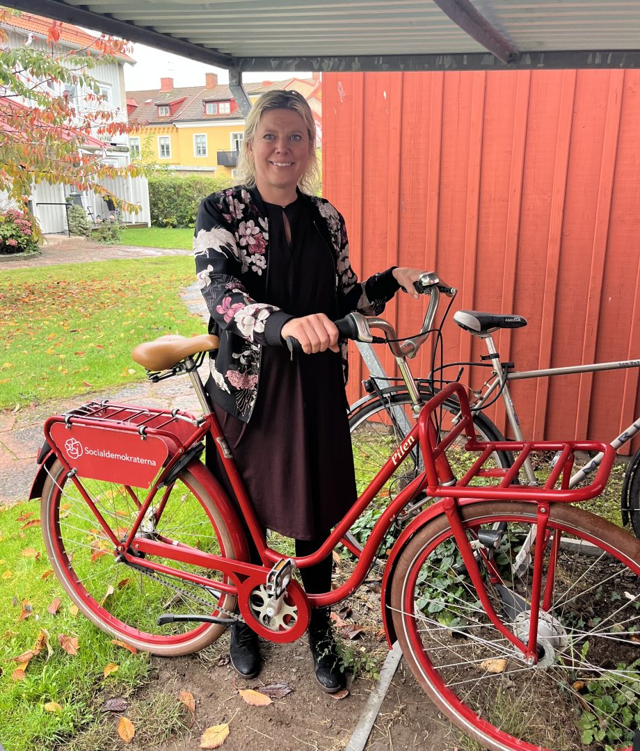 Kvinna som står vid en röd cykel.