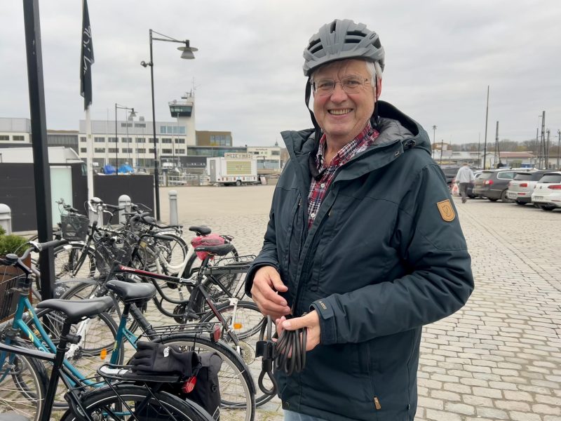 En glad man står bredvid sin cykel.