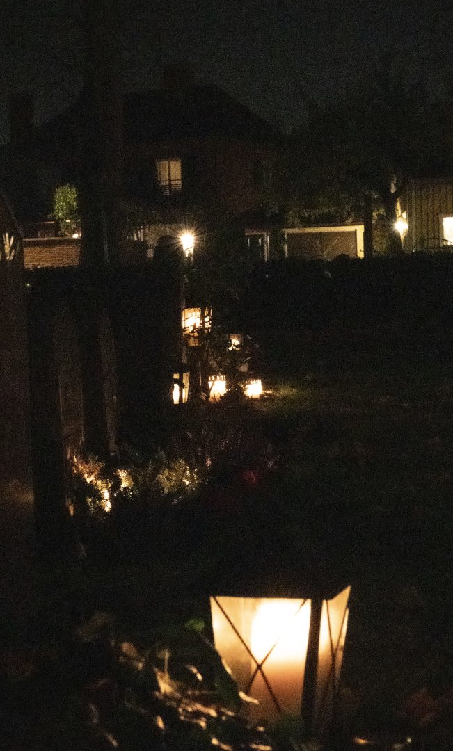 En rad av gravar där människor alla har tänt ett eller flera ljus.