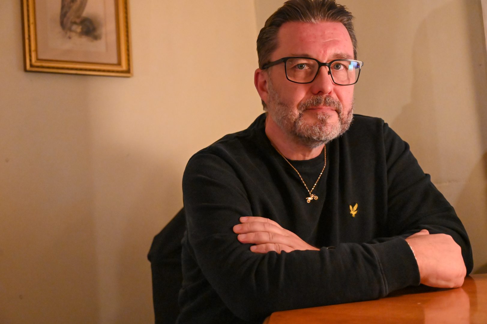 En porträttbild av Sam Cansund som sitter med armarna i kors vid ett bord