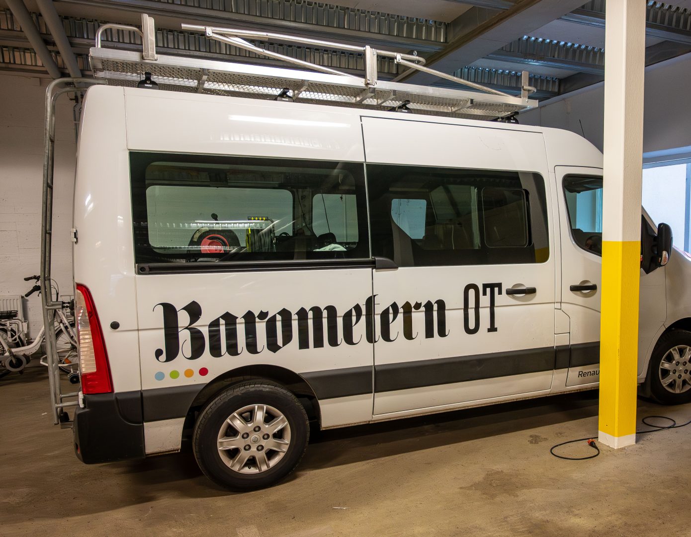 En minibuss som det står Barometern-OT på i ett garage.