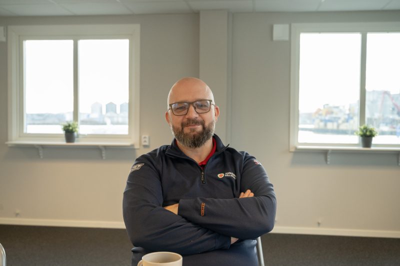 bild på man med glasögon sitter ner med armarna i kors. Två fönster för vardera sida.