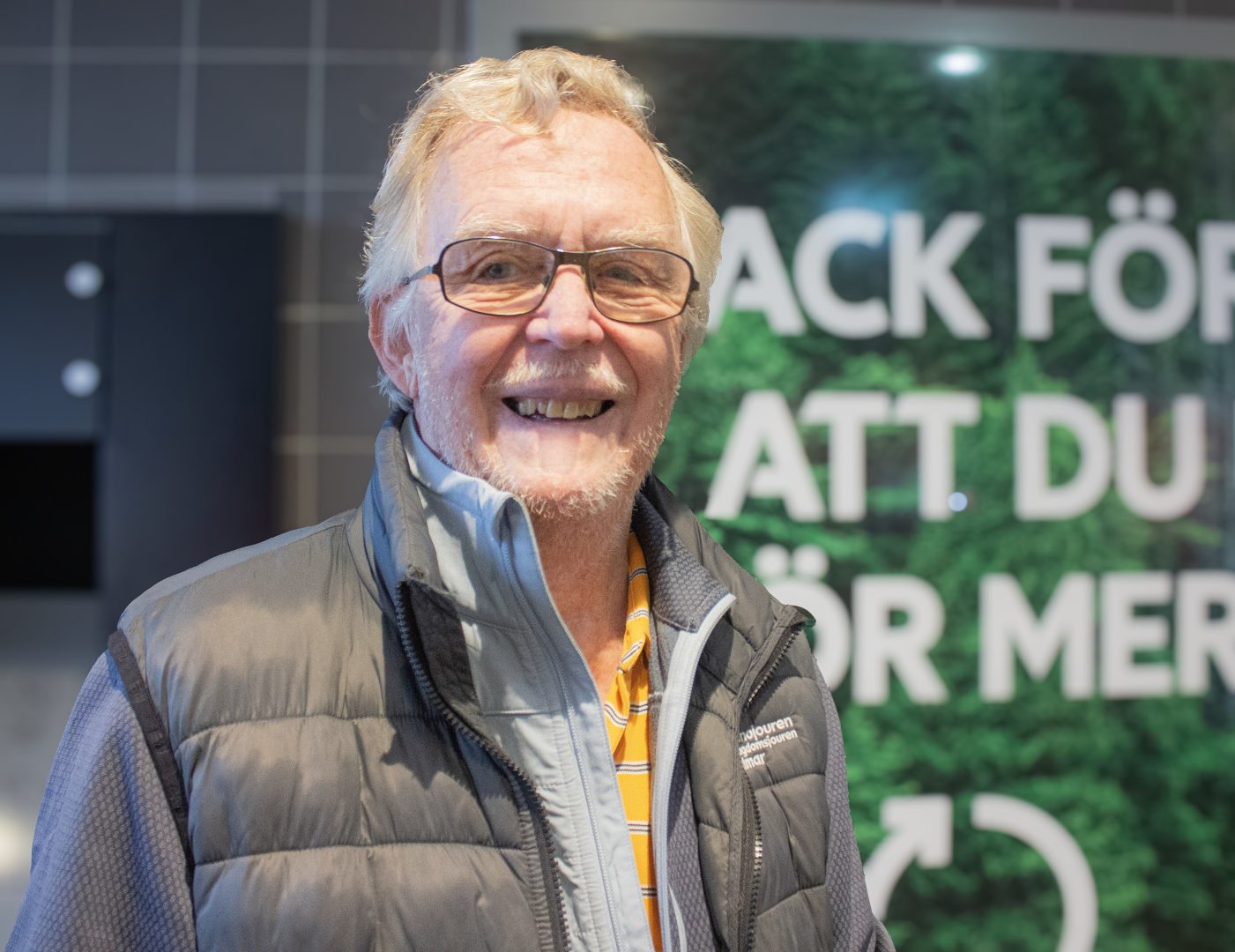 Kåre Eriksson tittar in i kameran och ler framför pantmaskin. Foto: Juwelia Jansson
