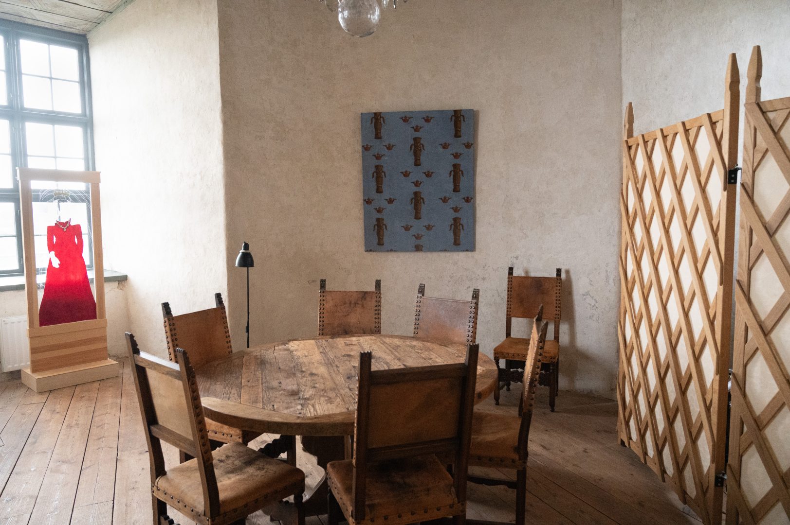 Ett gammaldags rum med många hörn och fönsternischer. I mitten av rummet står ett bord av träd med gammal utseende stolar runt omkring.