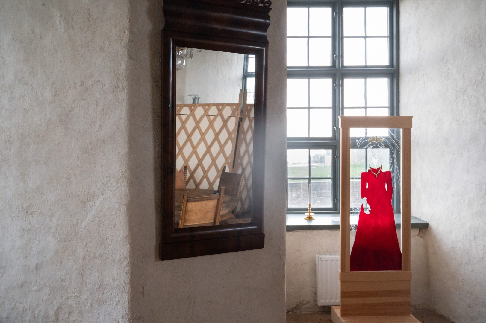 Stor, brun spegel i gammal stil på väggen till vänster. En fotoställare med en bild på drottning Margareta på höger sidan.